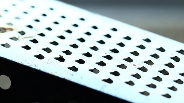 A close-up view of a metal grater with small holes, ideal for kitchen or food-related usage