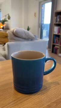 Ceramic&nbsp;blue&nbsp;coffee cup or tea cup with natural steam smoke. Close-up of Smoke rises from cup, cup of coffee for breakfast in the morning time with warm light. Hot Coffee Drink Concept.
