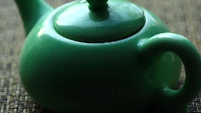 A green teapot sits on a table, ready for use