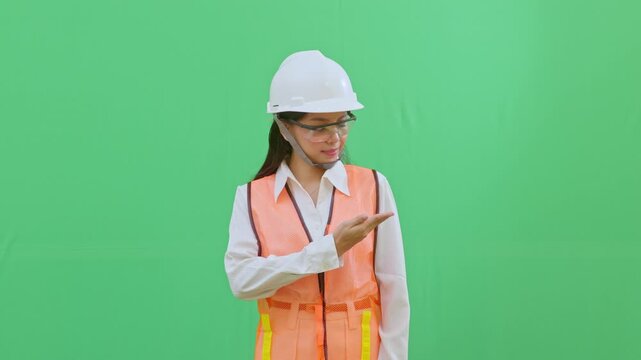 Female worker pointing at the blank chest area of her safety vest where a company logo would be. Perfect for corporate branding and identity videos.