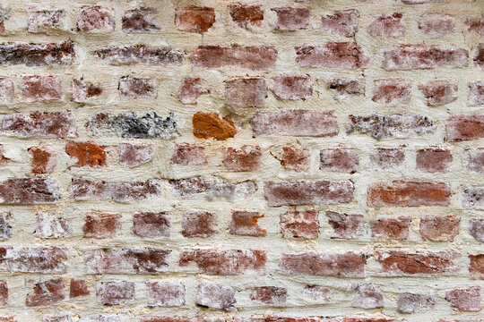 Old weathered red brick wall with concrete mortar joints providing a rustic background pattern. Full frame backdrop concept.