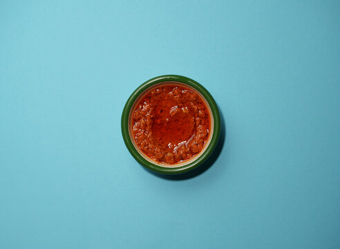 Fresh salsa served in a small green container on a light blue background