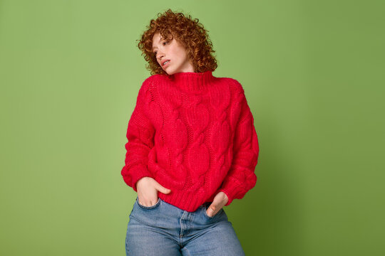 Red sweater style shines on a bright green background with a stunning young woman