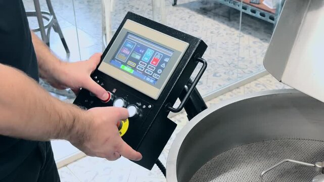 Professional Coffee Roaster Operator Releasing Freshly Roasted Brown Beans from Drum into Cooling Tray with Visible Steam and Mechanical Agitator Moving in Specialty Roastery Production Facility