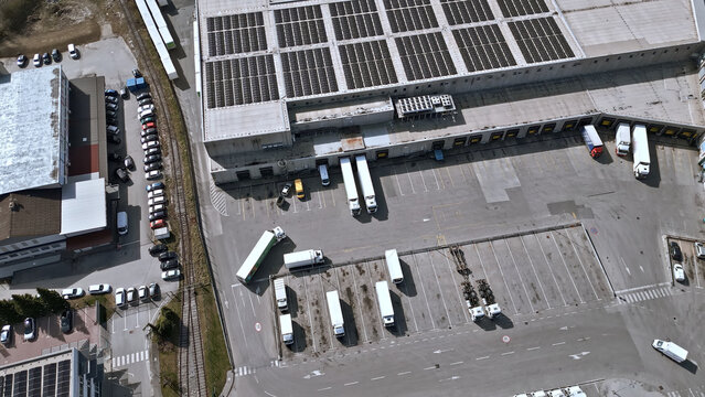 A bustling distribution warehouse, workers efficiently manage incoming and outgoing trucks. The organized chaos of freight transportation highlights the critical role of logistics in modern commerce.