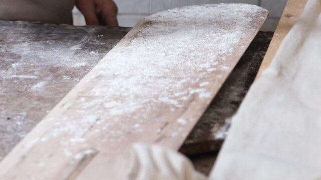 Sifting white flour through a traditional wooden sieve, slow motion.