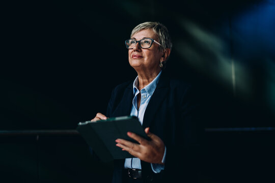 Senior female executive using tablet with a calm, focused expression. Represents digital maturity, confidence, and efficiency in mobile-enabled professional tasks.