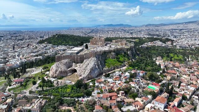 Aerial drone cinematic video of iconic Acropolis hill and the Parthenon a true ancient monument of Western Civilization with beautiful clouds, Athens historic center, Attica, Greece