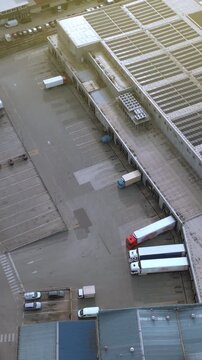 Aerial view of a distribution warehouse with multiple trucks lined up for freight transportation. The organized layout highlights efficient cargo container management at the station.
