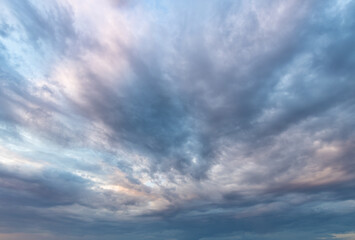 Obraz premium Dramatic clouds swirl above with soft blue and pink hues