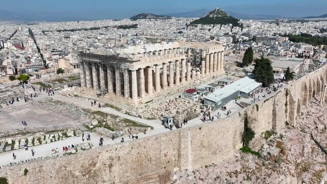 Aerial drone cinematic video of iconic Acropolis hill and the Parthenon a true ancient monument of Western Civilization with beautiful clouds, Athens historic center, Attica, Greece