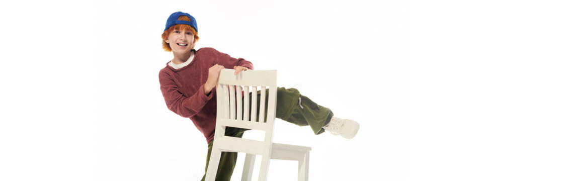 Bright and cheerful redhead boy explores fun poses in a modern studio setting