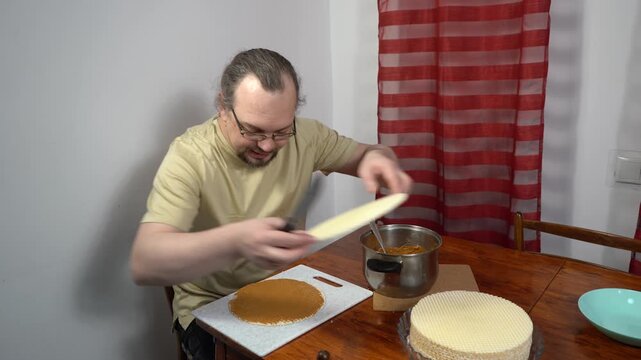 A man is making a waffle cake with condensed milk. Sweet food at home