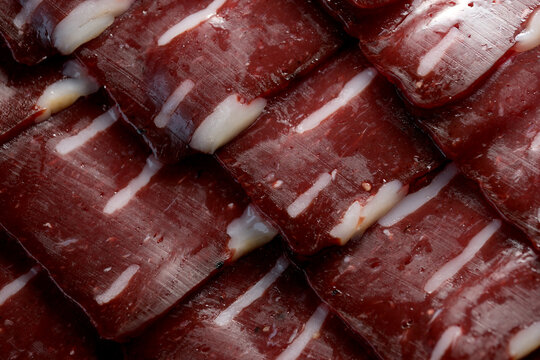 Savoring the rich layers of basturma slices on a wooden serving board