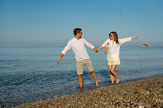 Happy couple holding hands walking on beach