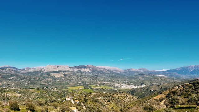 Wide view over a green valley with a white andalucian village. Colmenar, Malaga, Andalusia, Spain.