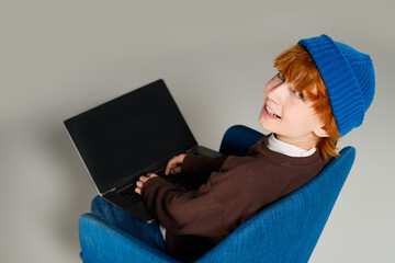 Creative redhead boy in a blue hat exploring fashion in a modern studio setting © LIGHTFIELD STUDIOS
