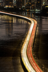 Panama city urban highway over water showing busy evening traffic with long exposure light trails and a illuminated cityscape in the background - stock photo