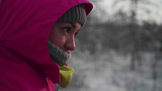 A person stands in winter clothes, looking thoughtfully into the distance. The setting shows snowy trees and a cold sky. The individual is engaged with their surroundings, reflecting on the beauty.