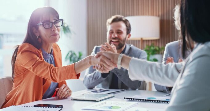 Business, people and meeting with handshake in office for agreement, celebration and finance deal. Women, shaking hands and team with applause for partnership, achievement and financial negotiation