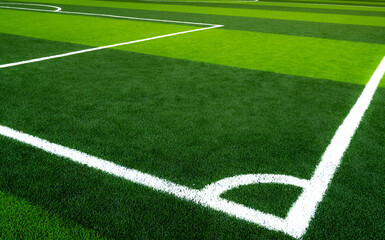 Obraz premium Green grass soccer field with white corner line marking on artificial turf, empty professional football stadium pitch outdoors, sports background for training, competition, and recreation concept.