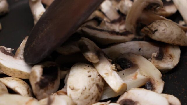 Stirring Champignon Mushrooms in Pan with Wooden Spoon Cooking Close Up