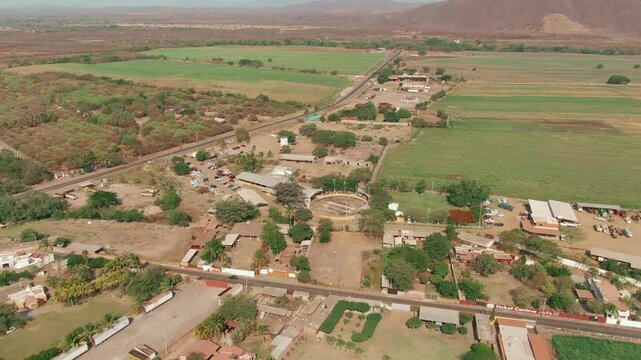 Drone footage captures a scenic aerial view of the Scaramuza contest arena in Colima, Mexico. Lush greenery, open fields, and clear sky set the vibrant, cultural ambiance.