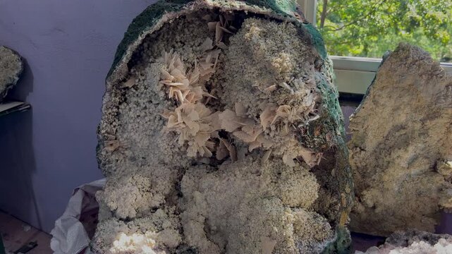 Mineral geode interior with bladed crystal rosettes and pale druzy textures revealed in a detailed close-up shot