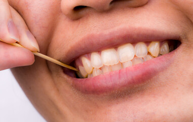 Fototapeta premium Asian woman removing food from teeth with wooden toothpick after eating, personal oral hygiene concept. Dental care routine, bad breath issue and natural bamboo tool used in daily lifestyle in Asia.