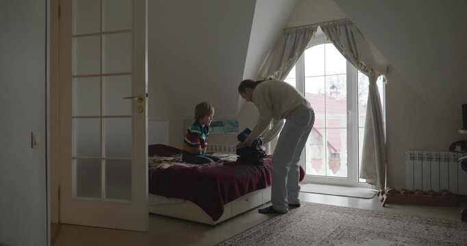 Man puts warm clothes on child. Dad help child to dress at home. 4K 10-bit