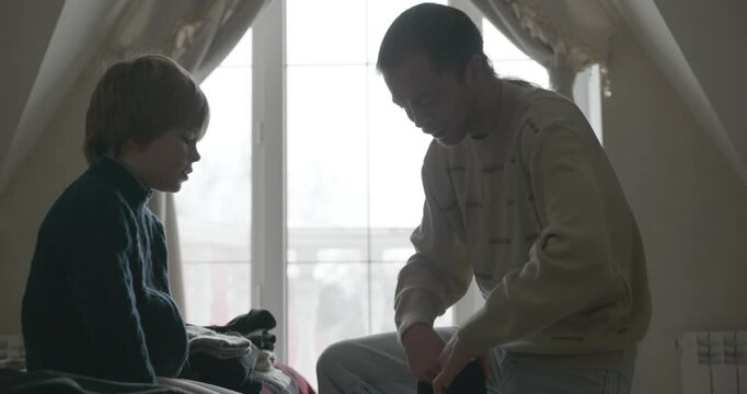 Man puts warm clothes on child. Dad help child to dress at home. 4K 10-bit