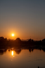 Fototapeta premium 美しい夕日を映す公園の池の水面 