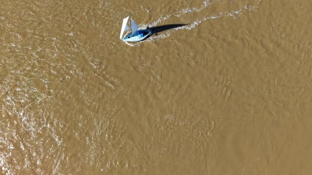 Aerial drone view of a small yacht sailing against the tide in the Deben Estuary, Felixstowe Ferry, UK