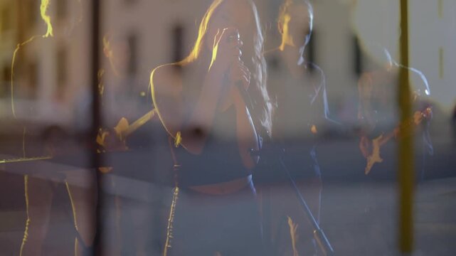 Music camera panning revealing lead singer moving center raising mic singing on glass for show