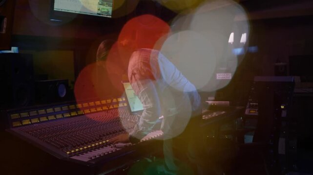 Playback starting, engineer adjusting faders and checking laptop while mixing, bokeh shifting
