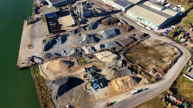 Aerial view of industrial aggregates and raw materials at the Port of Ipswich, shipping terminals with piles of sand, gravel and cement on the River Orwell in Suffolk, UK.