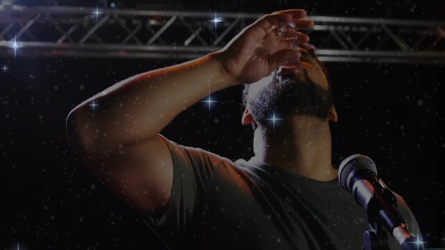 On vocal cue performer lifting shot glass, tilting and drinking, then raising arm celebrating song