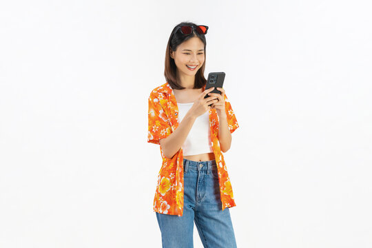 Portrait of young Asian woman in summer wearing floral shirt holding smartphone and smiling on white background.