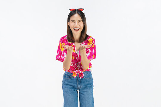 Cheerful young Asian woman in colorful summer floral shirt presenting empty copy space with open palm isolated on white studio background.