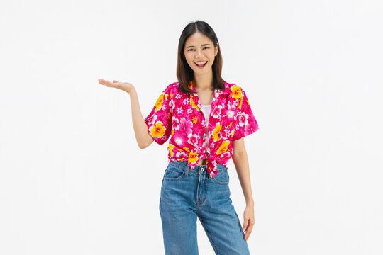 Smiling young Asian woman in colorful floral summer shirt standing and raise your hands isolated on white studio background.