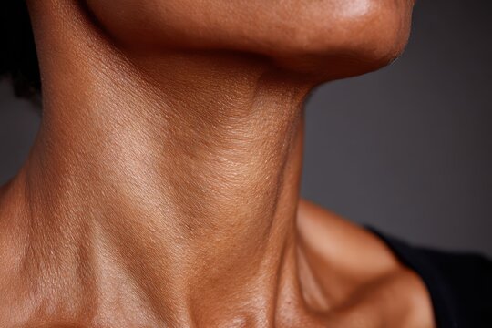 Close-up of a person's neck and jawline showing detailed skin texture and contours, highlighting natural beauty.