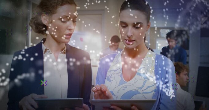 Right woman tapping tablet and explaining to peer, causing particle network overlay for business