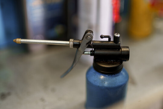 Blue hand oiler with a long nozzle on a workbench.
