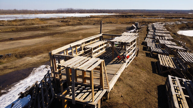 Aerial view of a dirt motocross track with stacks of wooden pallets in early spring