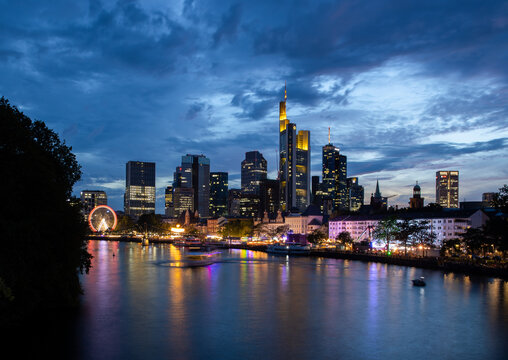 Frankfurt skyline at dusk with illuminated skyscrapers and river reflections, Germany