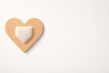 Fototapeta premium Adhesive plaster in heart shape. Symbol of psychological support, trauma recovery and soul healthcare.
