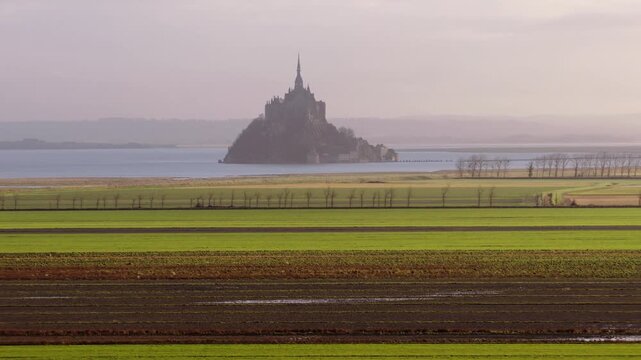 Aerial view of the historic Mont Saint-Michel abbey rising above the horizon with green agricultural fields in the foreground Mont Saint-Michel, Normandy, France.
