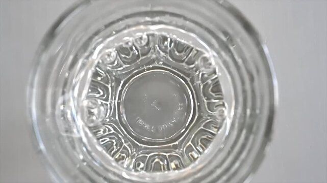 Top view of clear water ripples inside glass goblet with light reflection movement.