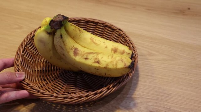 籐かごにバナナ・茶色いかごと黄色い果実・木製背景