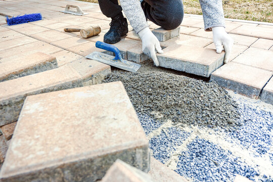 Person installing interlocking pavers for a new outdoor patio or walkway